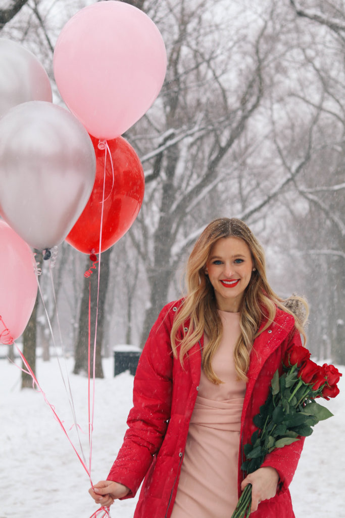 Lifestyle blogger Leigha Gardner of The Lilac Press in a blush pink Asos dress, red down puffer jacket heading down Commonweath Ave with Valentine's Day balloons and roses in tow.