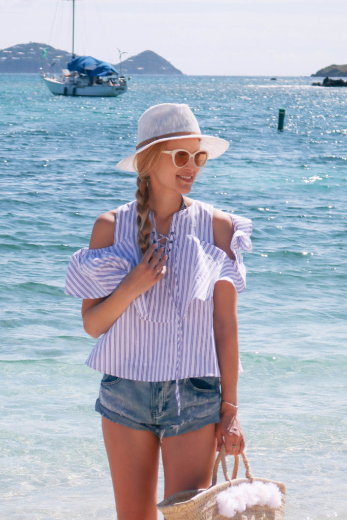 Lifestyle blogger, Leigha Gardner, of The Lilac Press walking on the beach in St. Thomas wearing a striped cold shoulder blouse and denim cutoffs. 