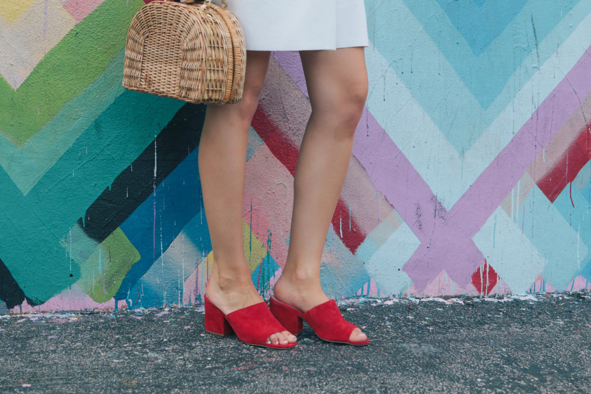 Fashion blogger, Leigha Gardner, of The Lilac Press exploring the colorful Wynwood district of Miami wearing a little white dress and red suede mules. 