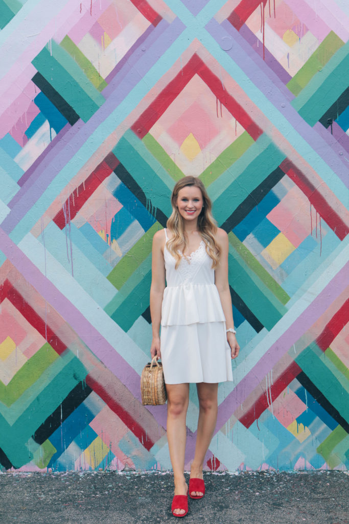 Fashion blogger, Leigha Gardner, of The Lilac Press exploring the colorful Wynwood district of Miami wearing a little white dress and red suede mules. 