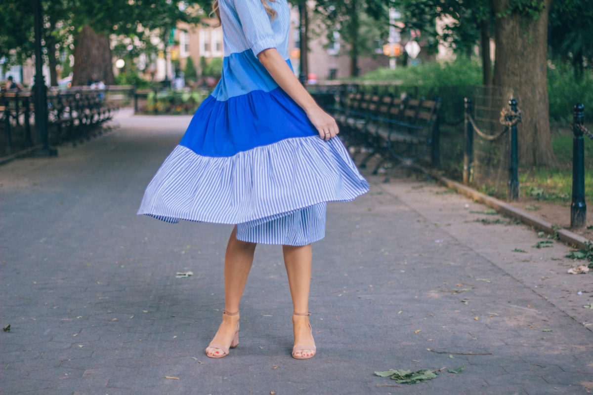 Style blogger, Leigha Gardner, of The Lilac Press sharing a favorite blue color blocked striped dress twirling around Washington Square Park, NYC.
