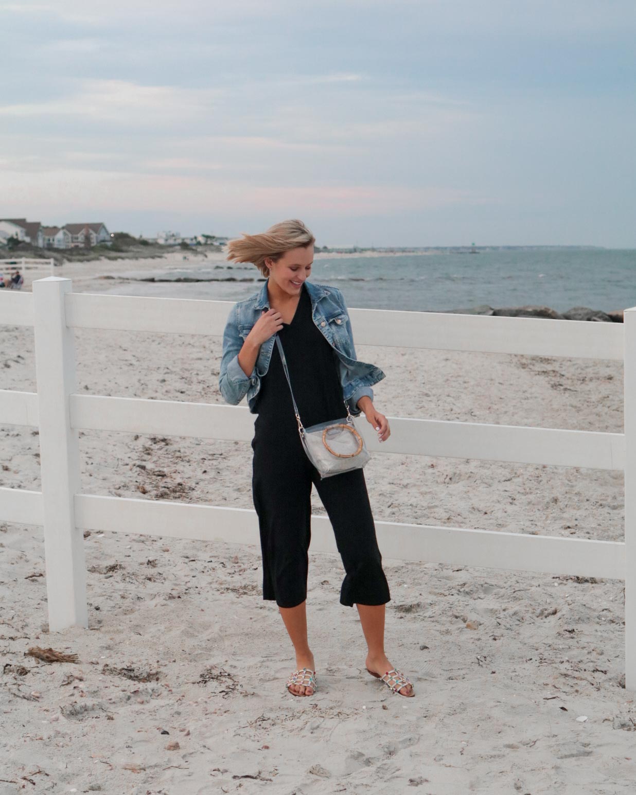 black knit jumpsuit styled with denim jacket and pvc crossbody bag