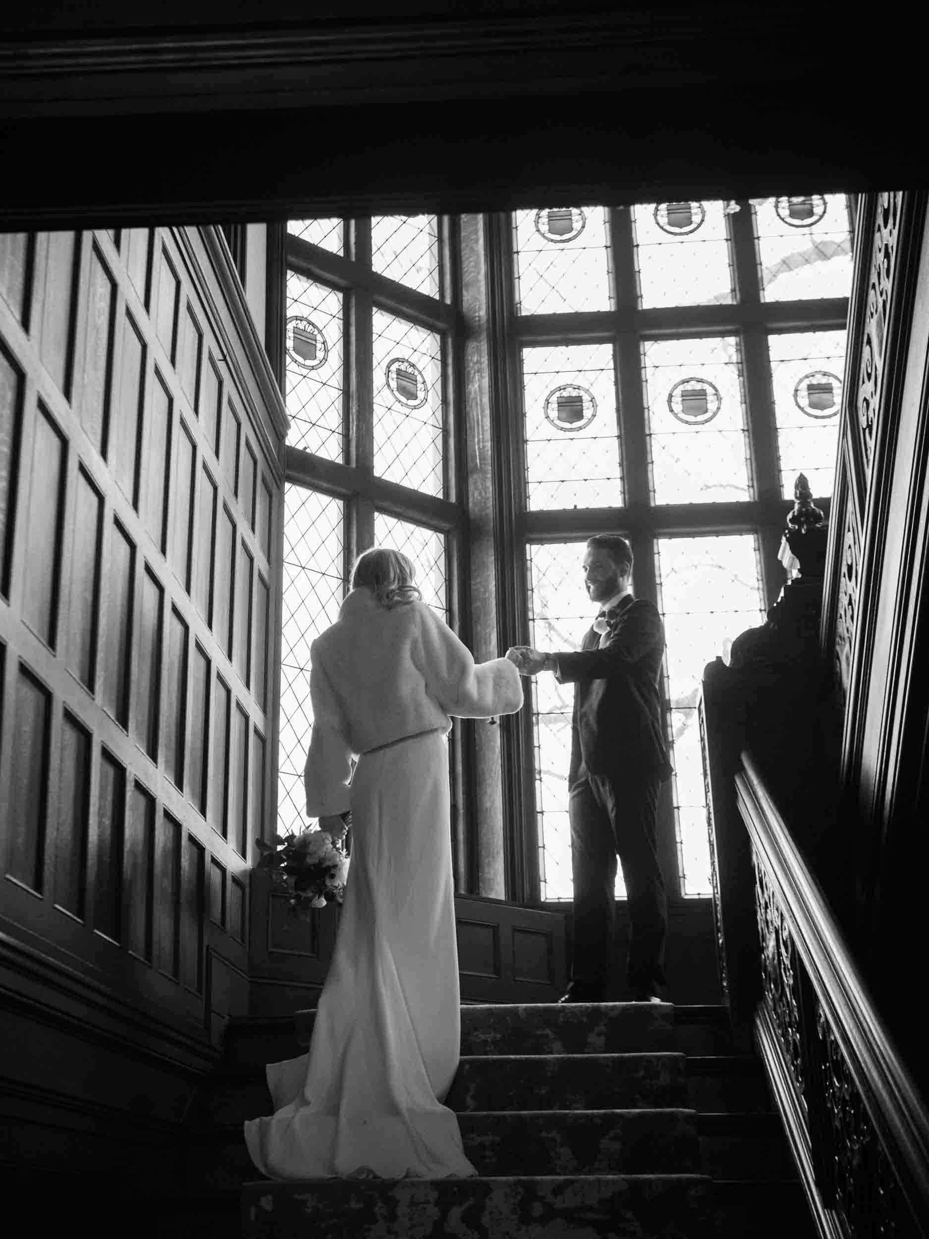 Groom leading bride up the stairs at gilded-age manor