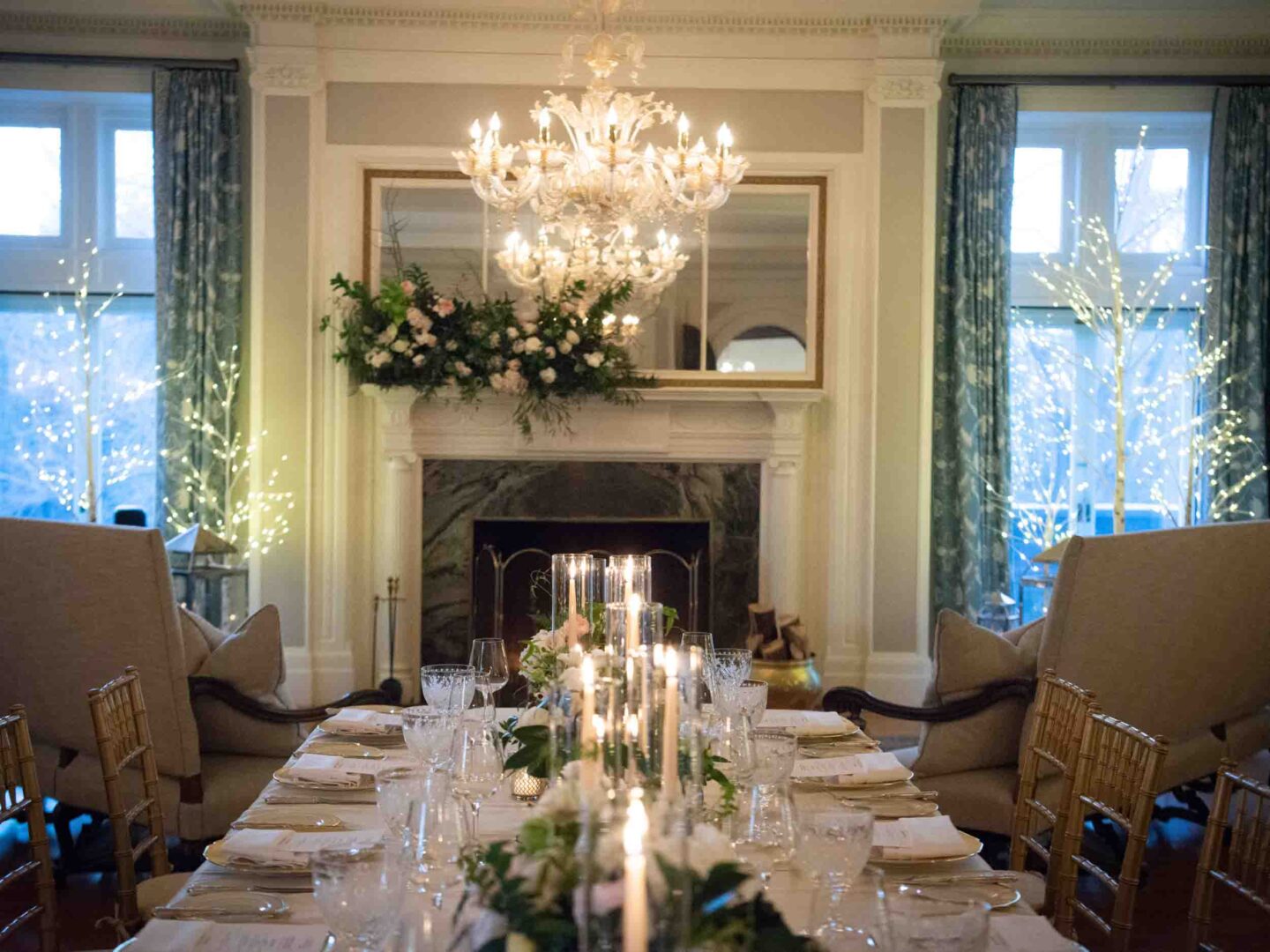 Tablescape with beautiful florals, cozy fireplace in the background and sparkly lit birch trees 