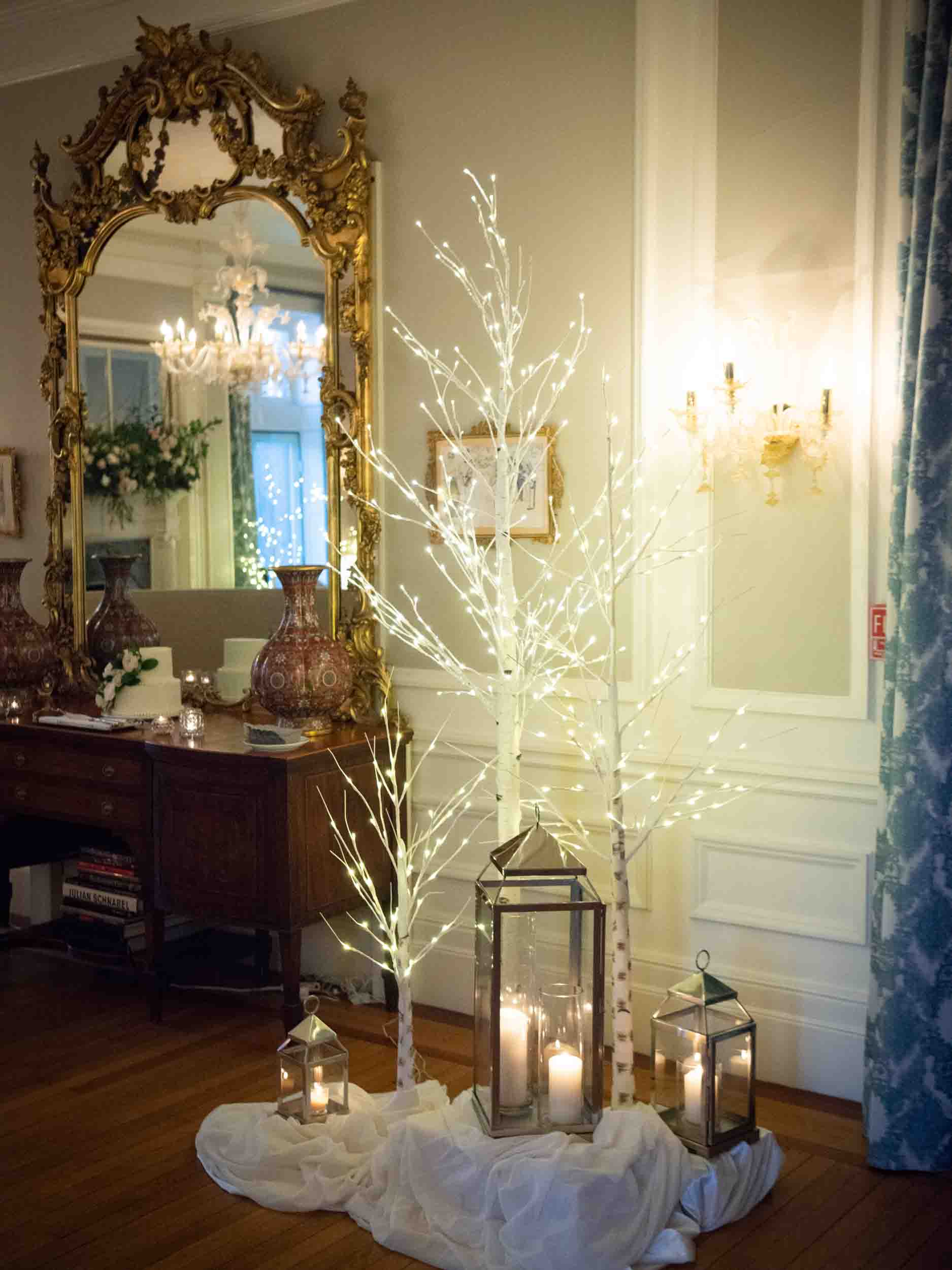 Cluster of white birch trees with sparkly lights, lanterns and candles