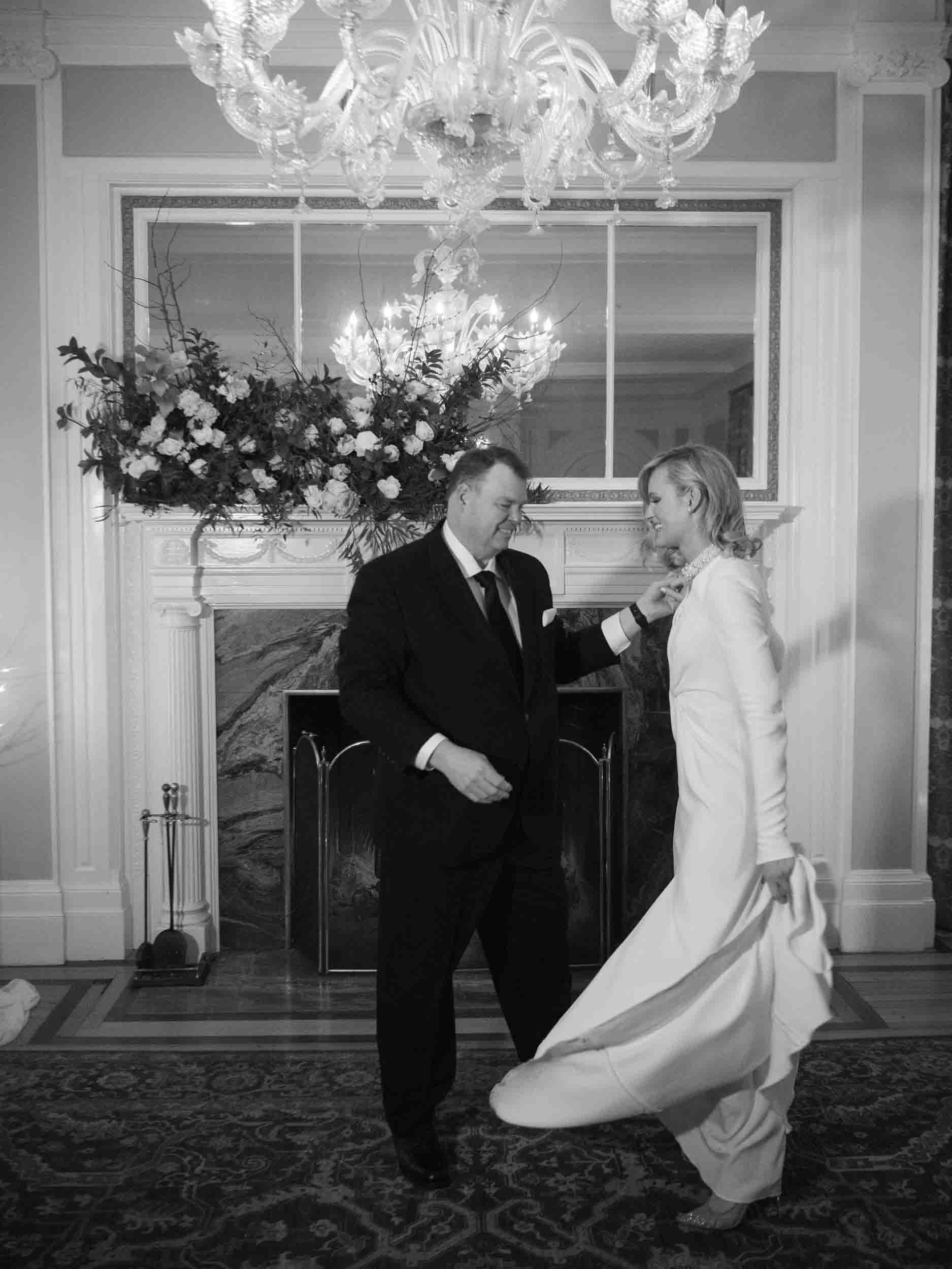 Bride dancing with father in front of the fireplace 